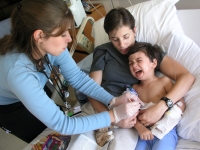 Samuel Habib is held by his mother, Betsy McNamara, as a nurse changes the dressing soon after Samuel, then 3, had a g-tube inserted into his stomach to improve his ability to take in foods and medicine.  Dan Habib photo