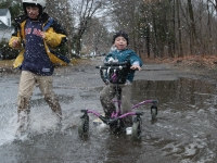 Samuel and Isaiah play in a puddle outside their home.  (Dan Habib/Concord Monitor)
