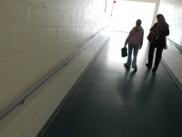 At the end of the school day, Alana walks down a hallway with an aide. “I think that having (an aide) with her all these years probably didn’t help her in making friends,” says special educator Karen Madeiros. Dan Habib photo