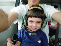 Samuel grabs the steering wheels of the sea plane owned by his grandfather, Walter McNamara, as he sits with his father, Dan Habib, shortly before take off.  Dan Habib photo